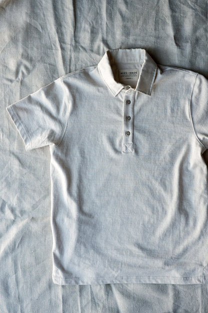Natural cotton short-sleeve rugby jersey polo laid flat, showing four-button placket and collar.