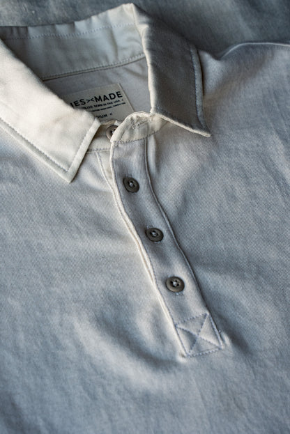 Detail of natural cotton rugby jersey collar with grey buttons and reinforced placket stitching.
