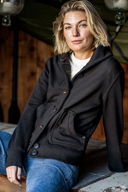 Woman wearing the Bodega shawl collar French terry cardigan in basalt black with tobacco contrast stitching, paired with.