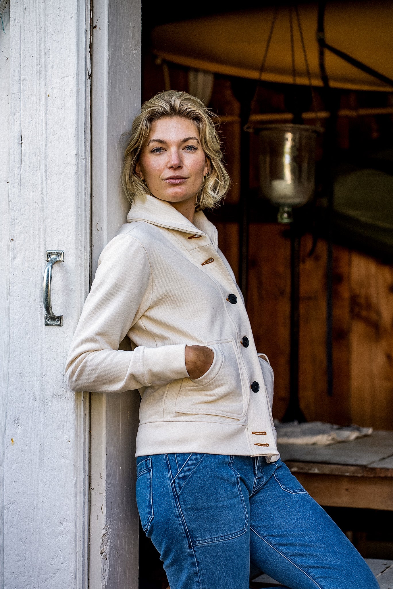 Natural French terry Bodega cardigan worn open over blue jeans, contrast keyholes and buttons visible.
