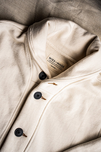 Close-up of natural cotton French terry cardigan with black buttons and tobacco keyhole stitching.