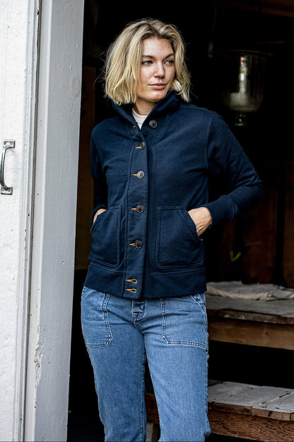 Model wears navy Bodega shawl-collar cardigan with contrast keyholes, buttoned over jeans.