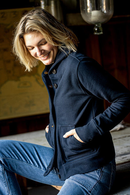 Navy French terry Bodega cardigan worn buttoned with hands in front pockets.