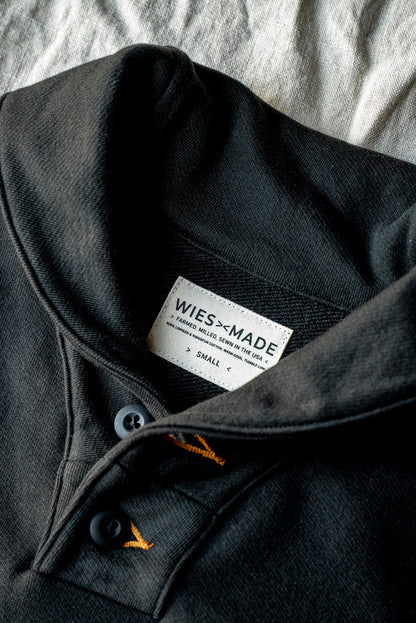 Close-up of the Basalt shawl collar pullover showing button placket, contrast gold stitching, and WiesMade USA-made label.