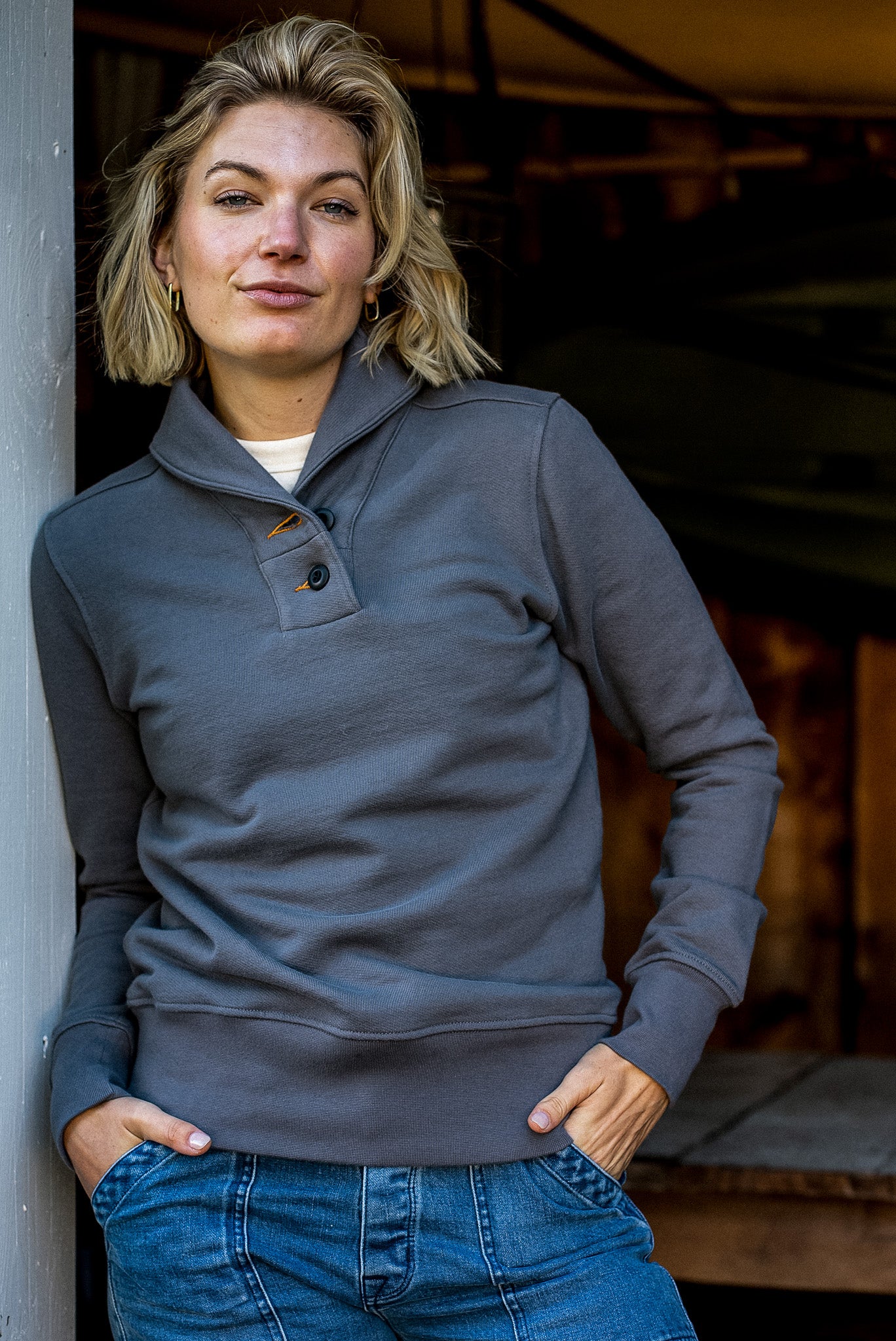 Woman wearing gray Bodega shawl collar French terry pullover with button placket over jeans.