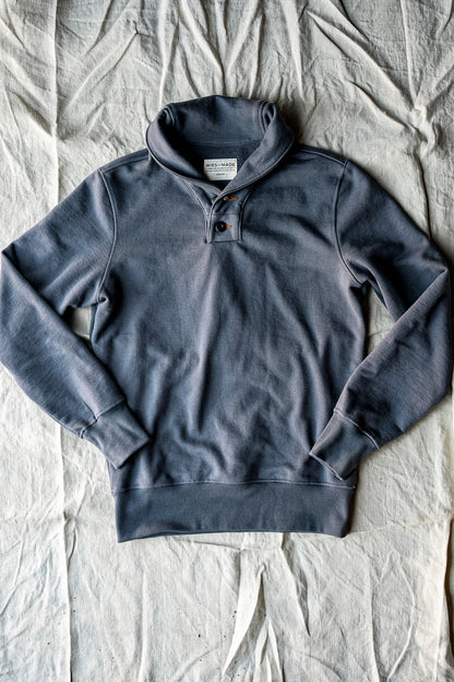 Pebble gray shawl collar French terry pullover laid flat on natural linen fabric.