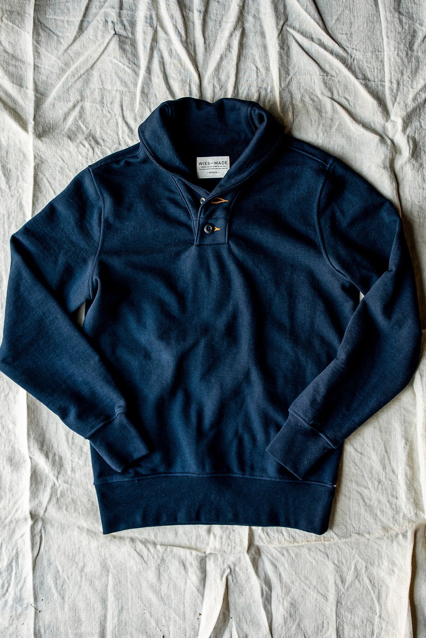 Navy French terry shawl collar pullover laid flat with button placket and WiesMade label.