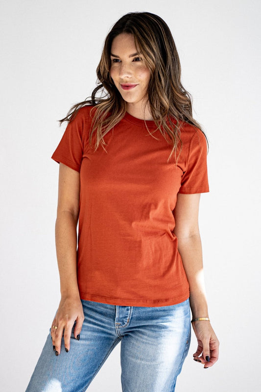 Woman wearing a brick-red heavyweight cotton crewneck tee with blue jeans.