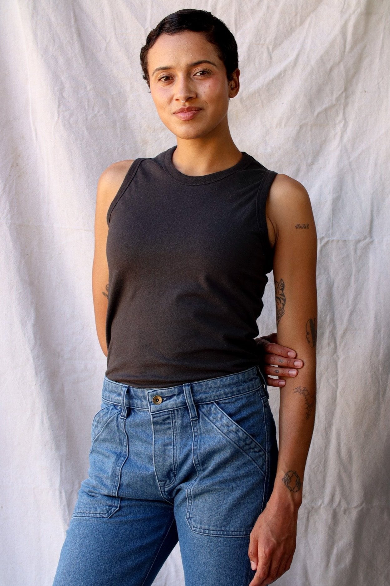 Model wearing the Bolinas basalt cotton tank tucked into light-wash denim jeans.