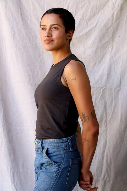 Side view of the Bolinas basalt cotton tank tucked into blue jeans against a linen backdrop.