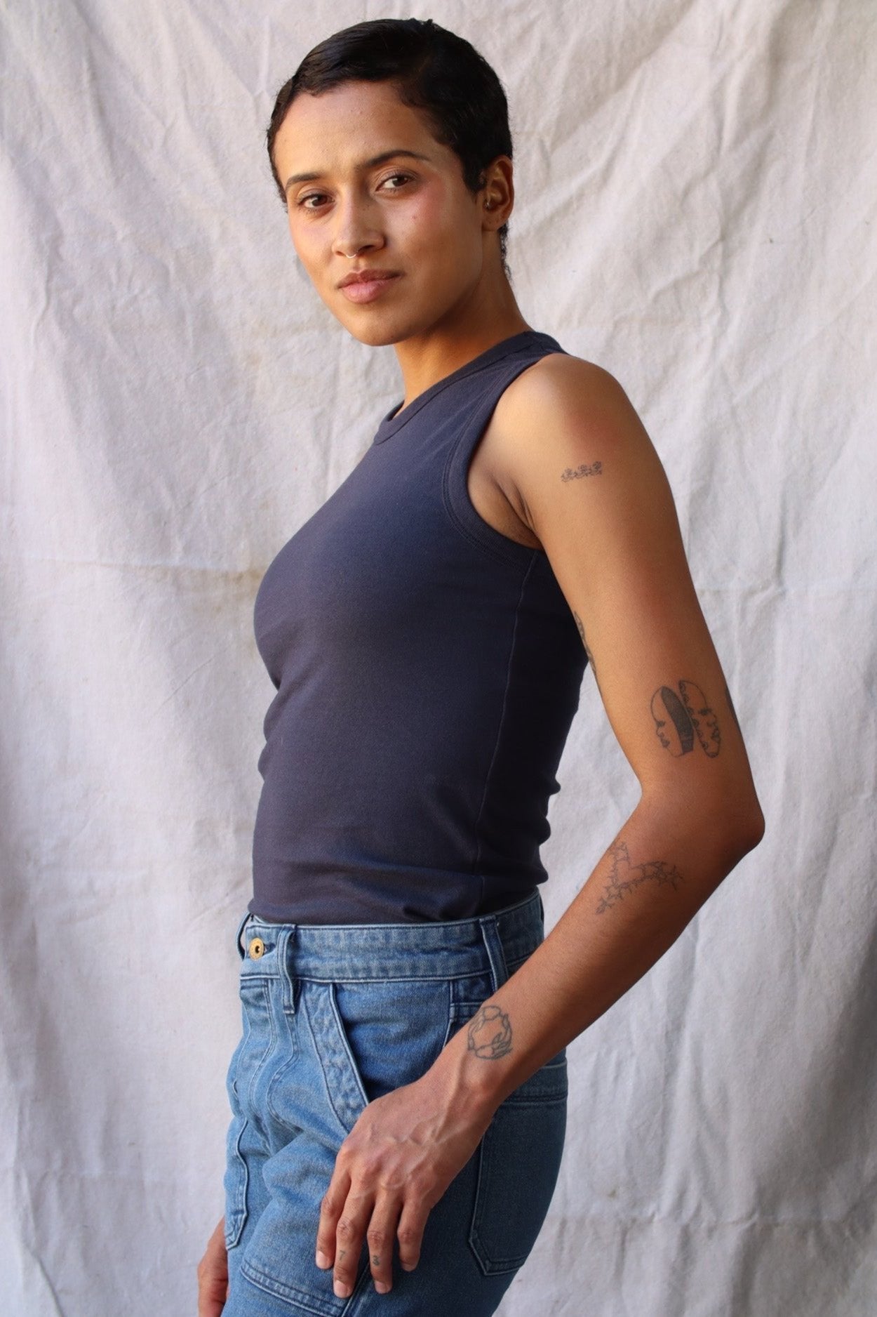 Side view of the Bolinas cotton tank in polar blue-grey, worn tucked into blue denim jeans.