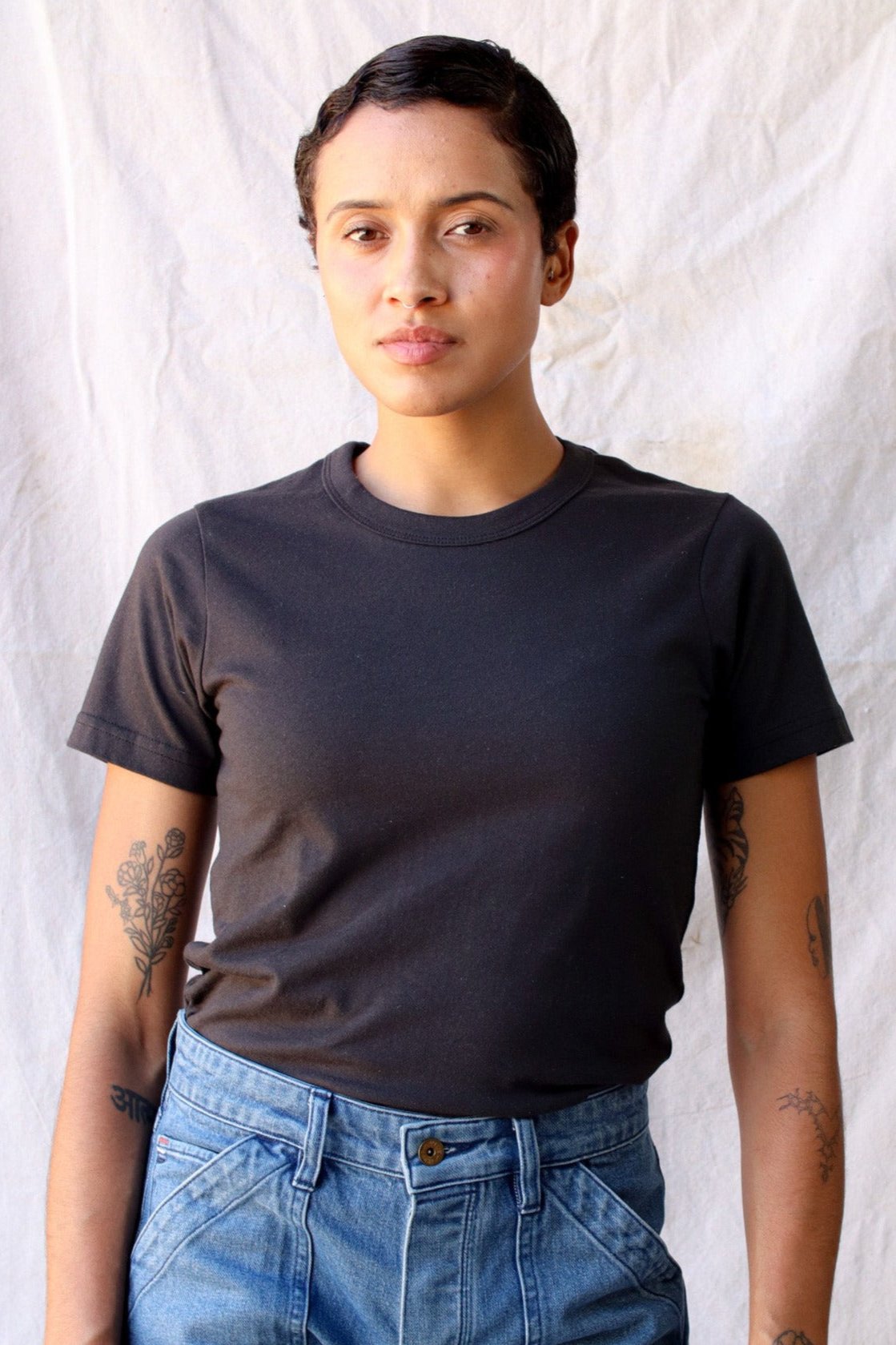 Woman wearing the Bolinas heavyweight tee in basalt black with high-waisted blue jeans.