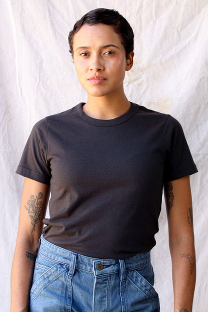 Woman wearing the Bolinas heavyweight tee in basalt black with high-waisted blue jeans.