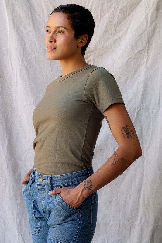 Side view of the olive Bolinas heavyweight tee styled with light-wash jeans against a canvas backdrop.