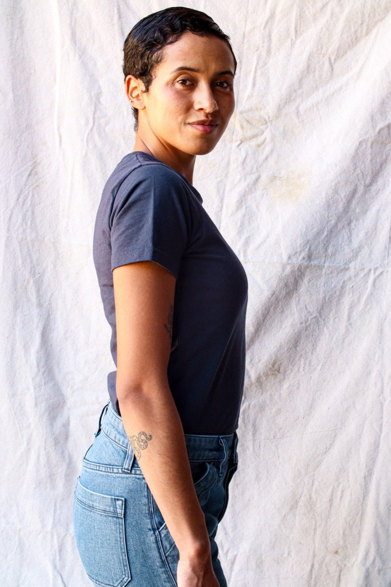 Side view of the Bolinas heavyweight tee in polar navy, paired with light wash jeans against a canvas backdrop.