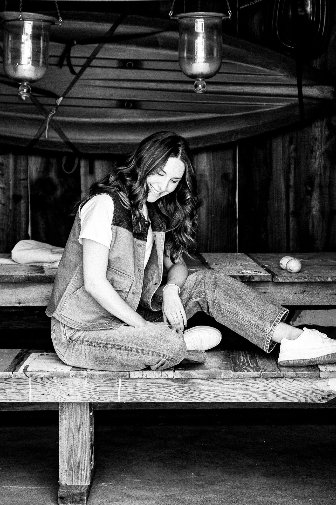 Person in wheat broken twill denim vest with button pockets, seated on a wooden bench.
