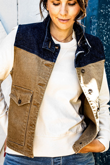 Woman wearing wheat broken twill denim vest with contrast navy yoke and brass buttons.