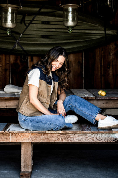 Woman in a wheat broken twill denim vest sitting on a wooden bench.