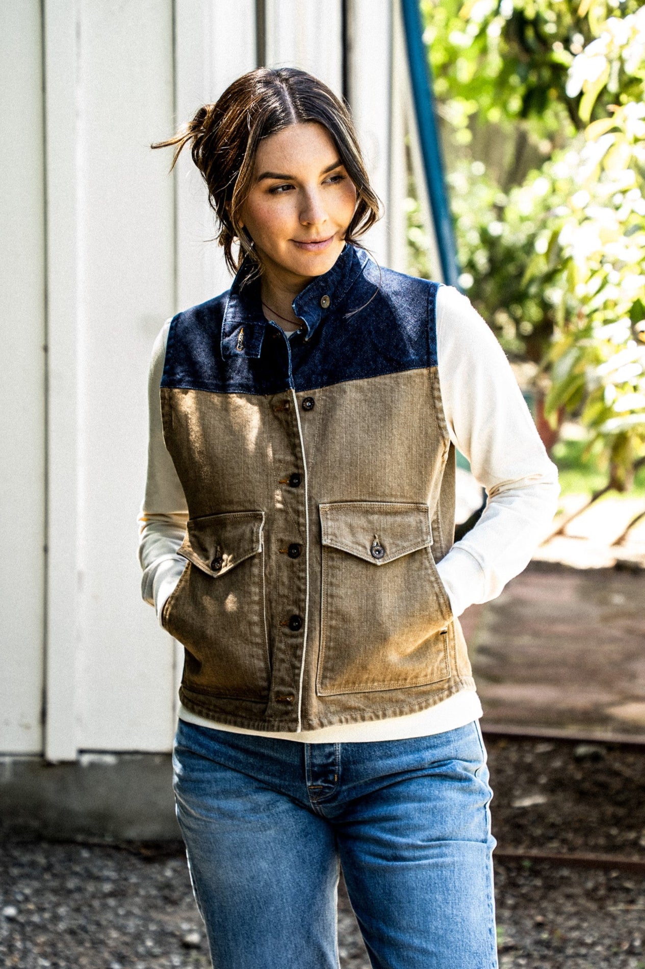Woman wearing wheat and navy two-tone Jamie denim vest with button-flap pockets outdoors.