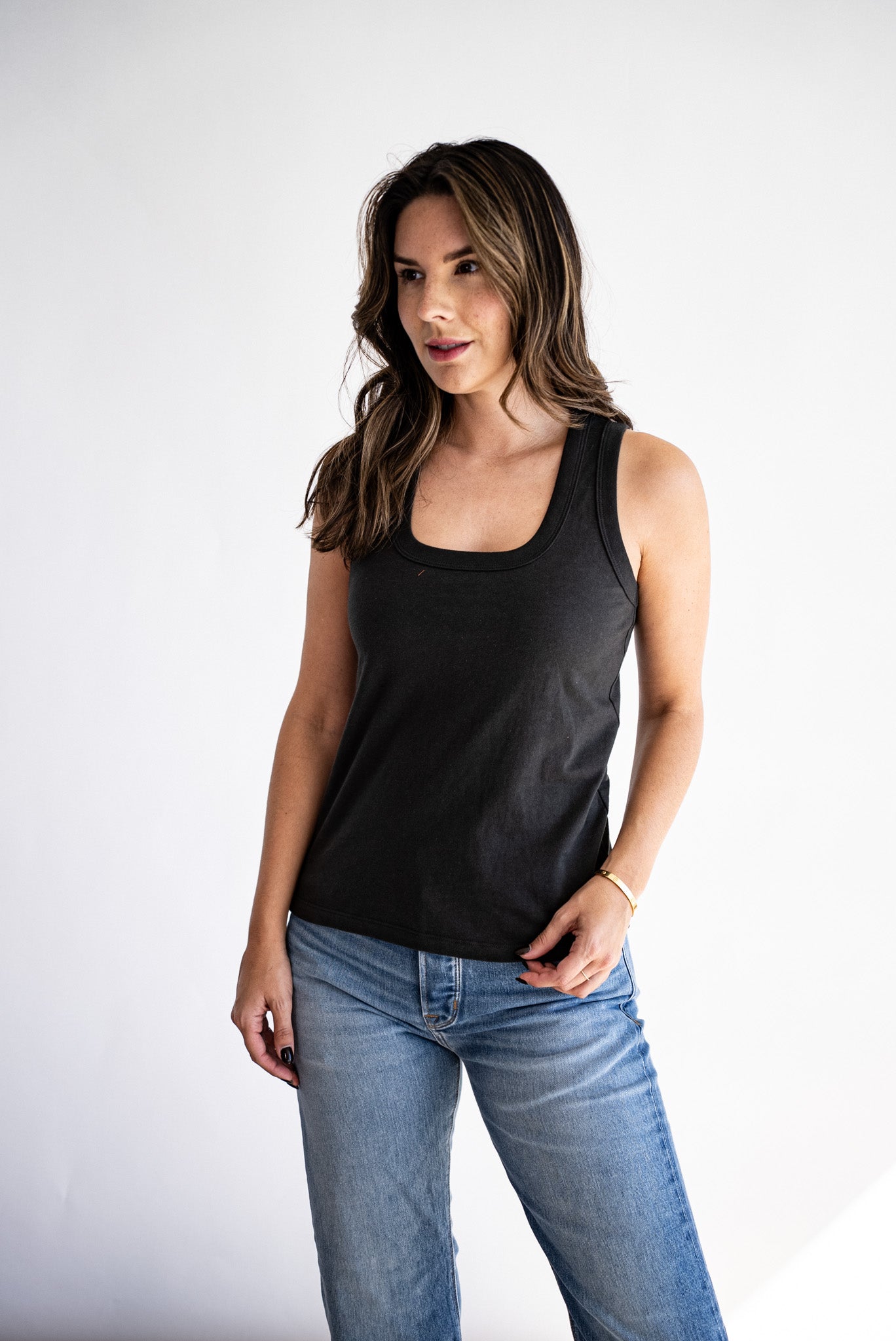 Model wearing the Reyes scoop-neck cotton tank in basalt black with light wash jeans.