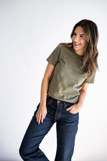 Woman wearing an olive Reyes boxy tee tucked into dark raw denim jeans.