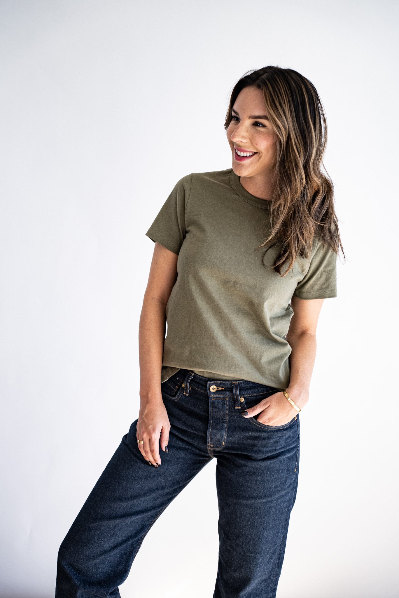 Model wearing the olive Reyes boxy tee styled with dark denim jeans.