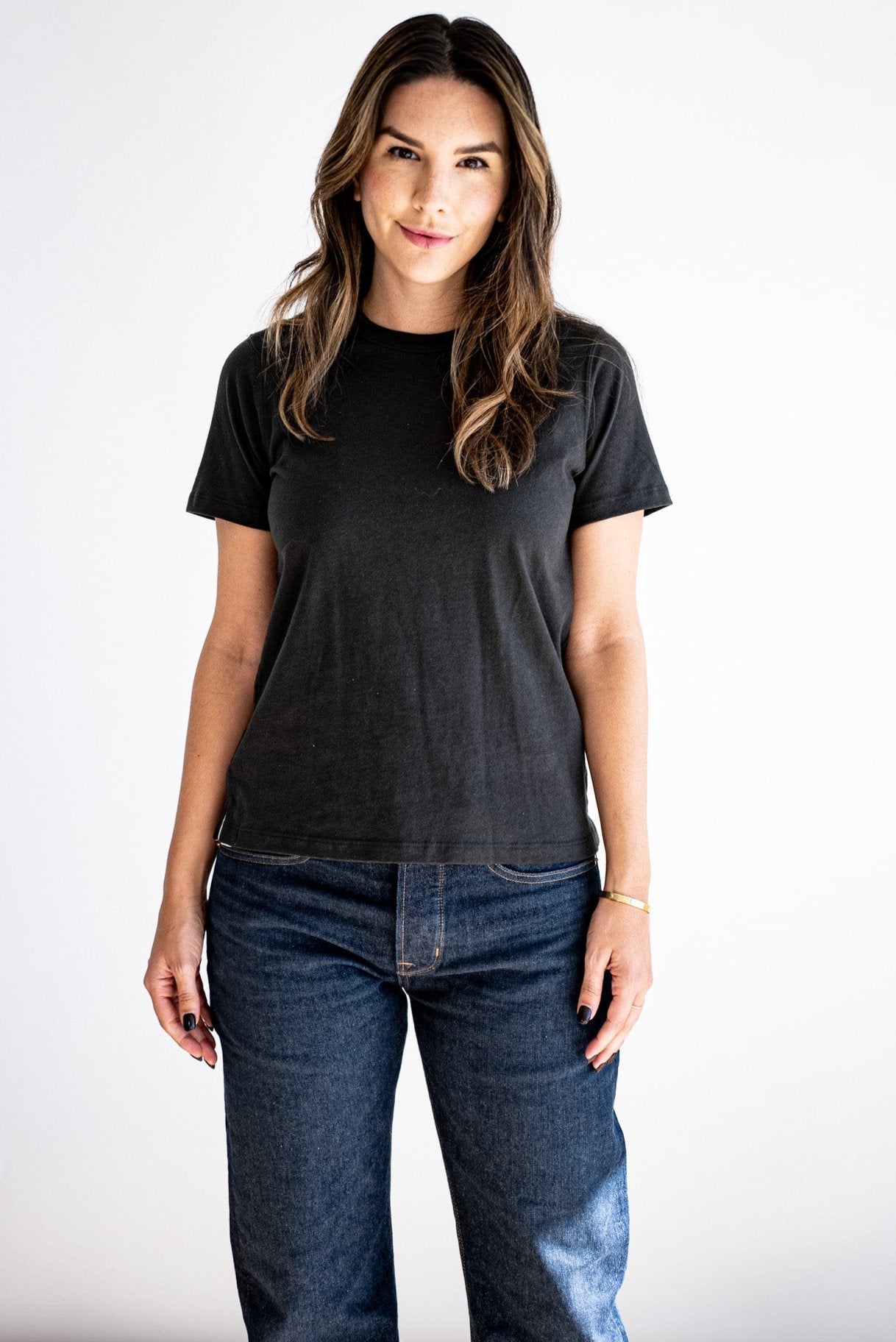 Woman wearing the Reyes boxy tee in basalt black, paired with dark wash denim jeans.