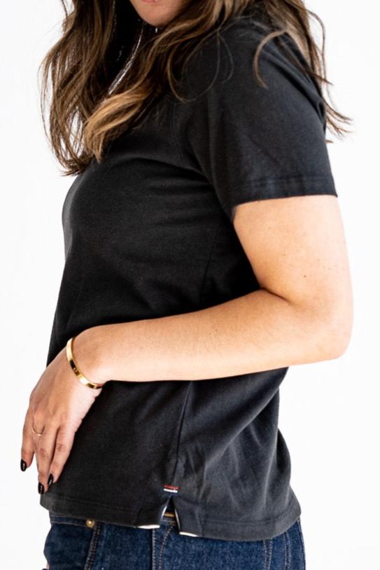 Side view of the Reyes boxy tee in basalt black, showing relaxed fit, side vent, and hem bartack detail.