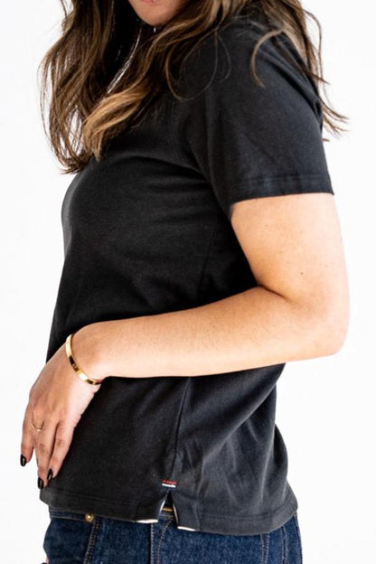 Side view of the Reyes boxy tee in basalt black, showing relaxed fit, side vent, and hem bartack detail.