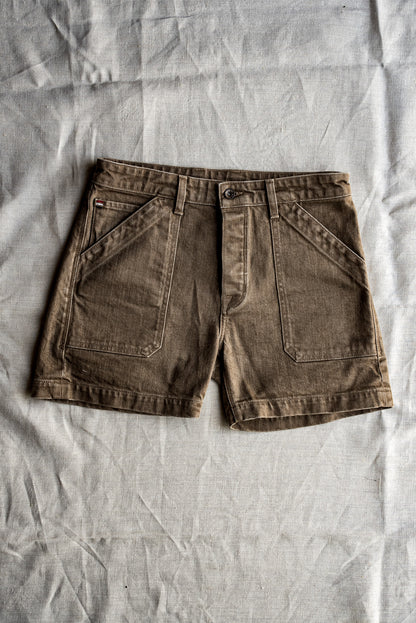 Wheat-toned Scout military denim shorts laid flat on natural linen, showing angled pockets.