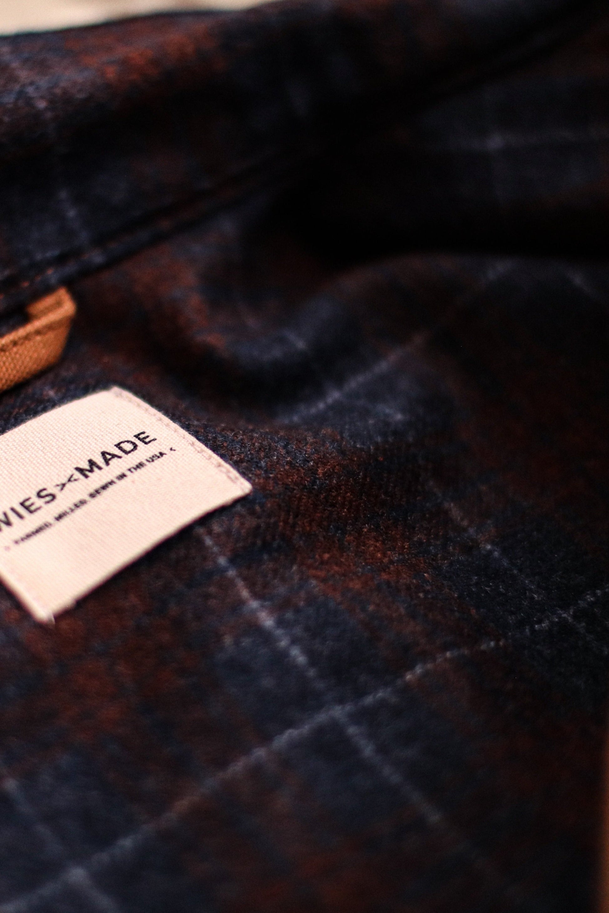 Close-up of the Jamie Vest's navy and rust wool plaid lining with a WiesMade sewn-in label.