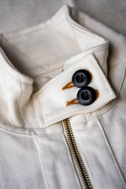 Detail of women's natural cotton moto jacket collar with black buttons and brass zipper.