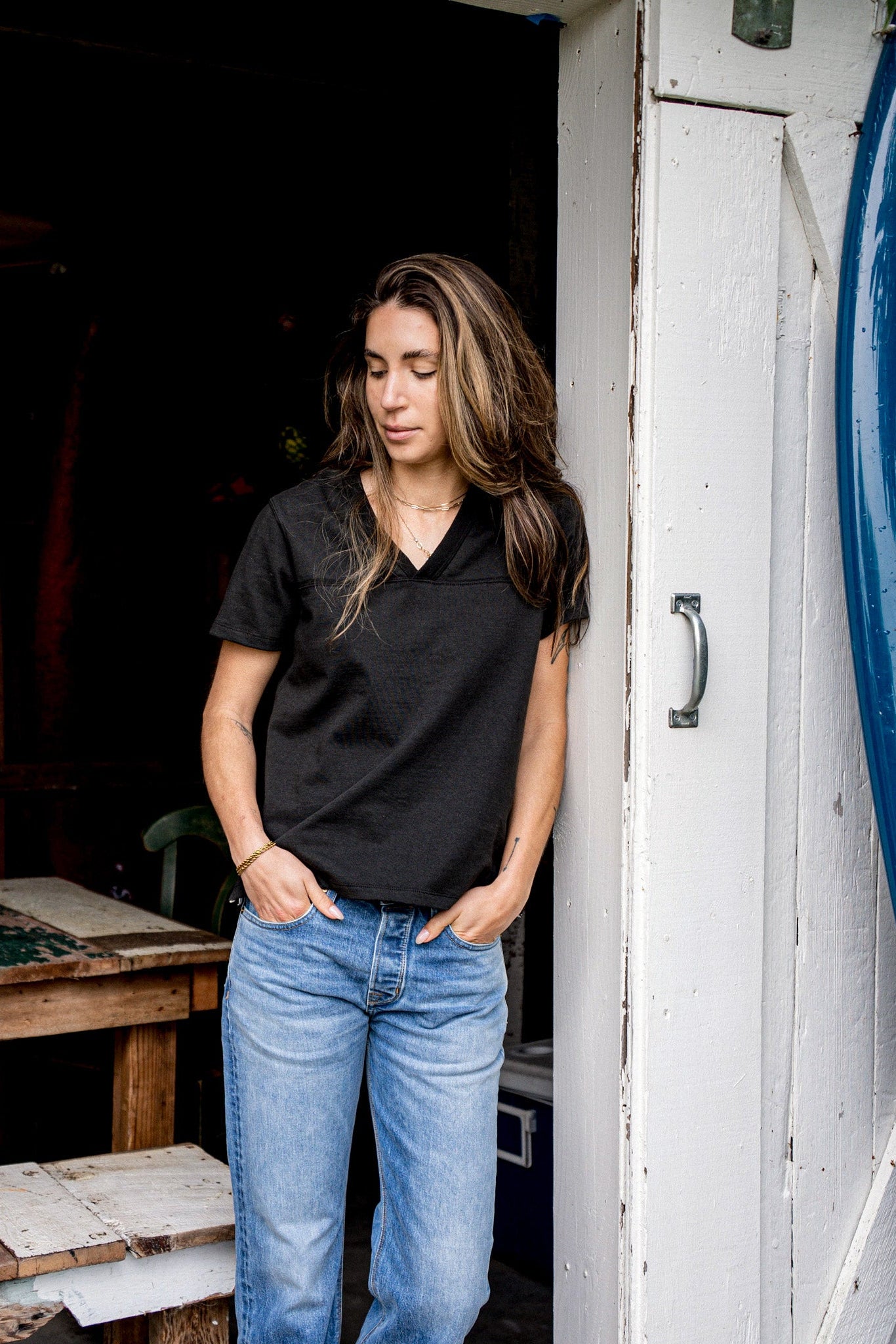 Leaning in a doorway, a person wears the Basalt V-neck cotton jersey with blue jeans.