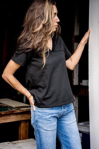 Person in dark basalt Stinson V-neck cotton jersey with jeans, side profile by doorway.