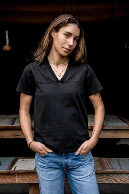 Person wearing basalt black Stinson V-neck cotton jersey tee with jeans, showing yoke seam.