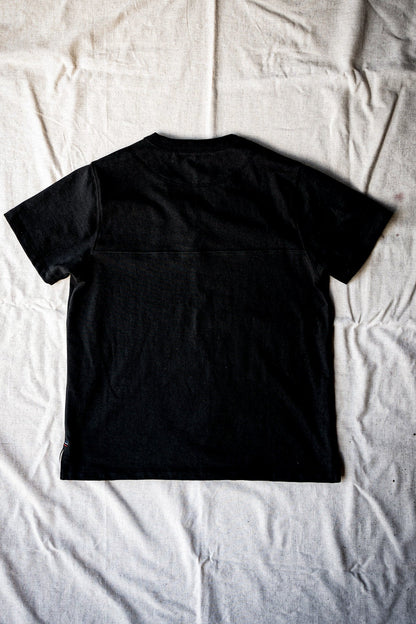 Basalt black cotton jersey tee shown from the back, flat-laid with visible yoke seam.