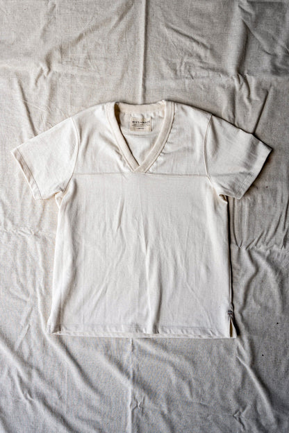 Natural cotton women's V-neck jersey tee laid flat, showing yoke seam and WiesMade label.