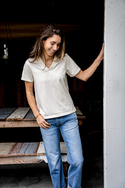 Person wearing natural Stinson V-neck cotton jersey tee with jeans in a doorway.