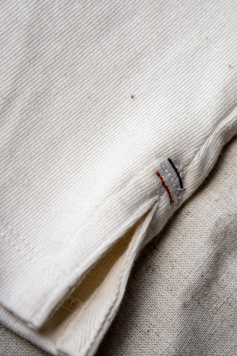 Natural 12oz cotton jersey hem with red, white, and blue triple bartack stitching and side vent.