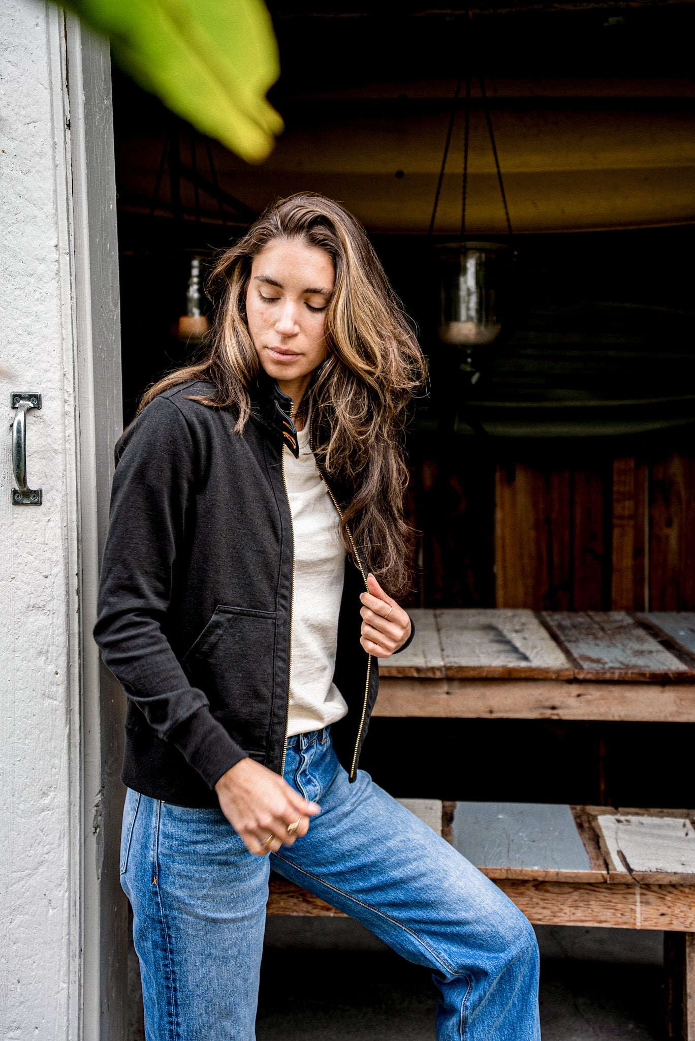 Person wearing basalt black Stinson Moto cotton zip jacket with brass zipper and jeans.