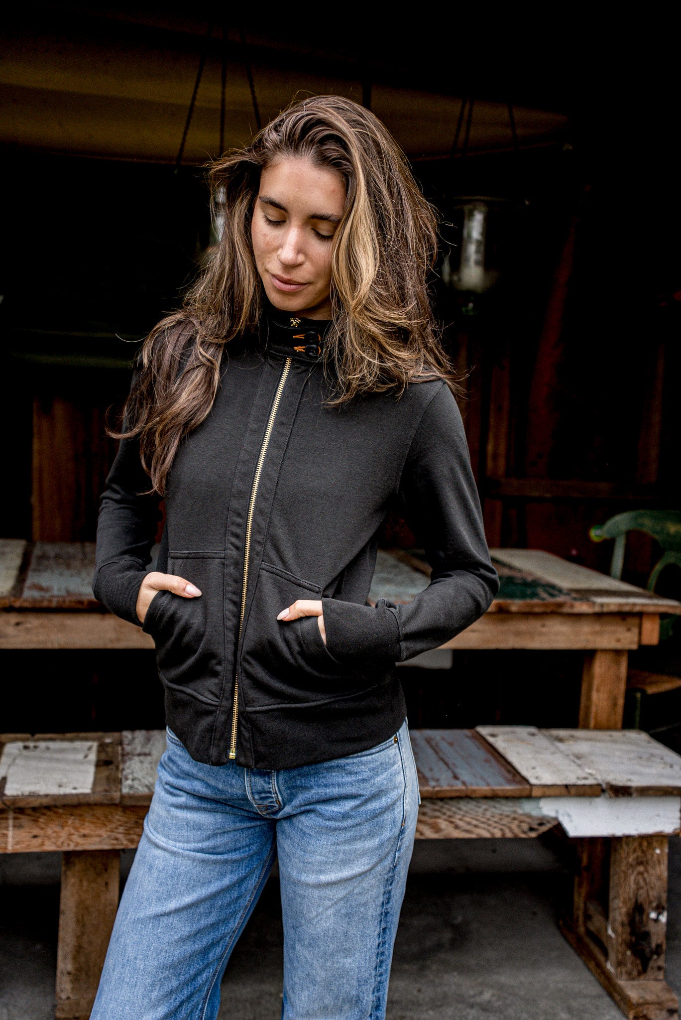 Person wearing a basalt cotton Stinson moto jacket with brass zipper, hands in front pockets.