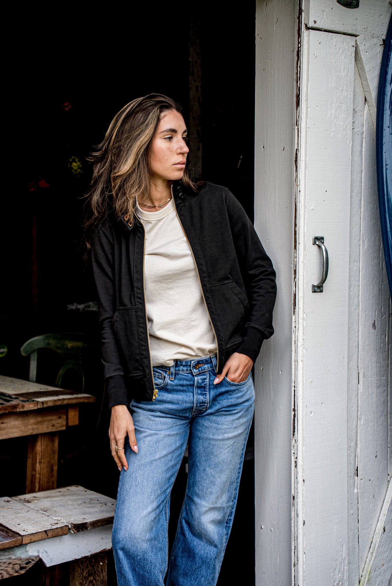 Woman wearing an open women's cotton moto jacket with brass zipper over a cream tee.