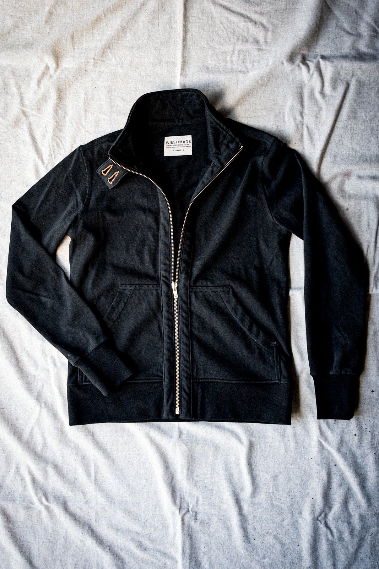 Women's basalt cotton moto jacket flat-lay showing brass zipper and stand collar.