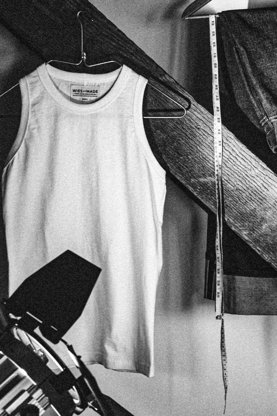 WiesMade Reyes boxy tank in cotton jersey on a hanger beside a measuring tape and denim, shown in black and white.