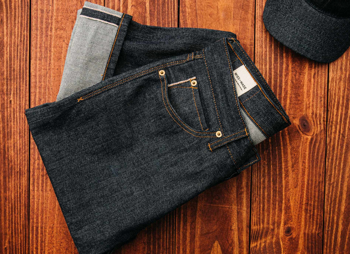 Selvedge denim jeans made in the USA neatly folded on a wooden surface, showcasing premium raw denim texture, reinforced stitching, and traditional craftsmanship for timeless quality