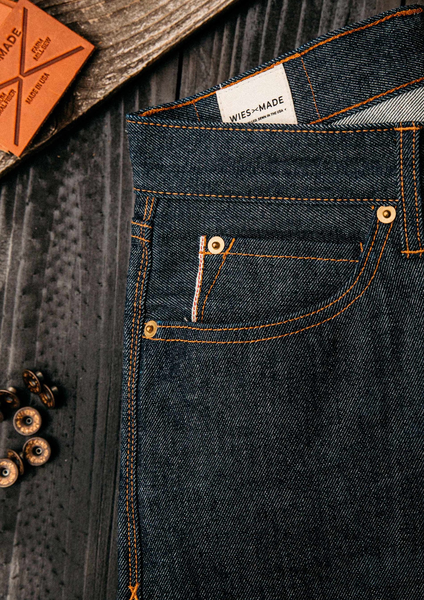 American selvedge denim jeans close-up showcasing premium raw denim texture, copper rivets, and contrast stitching, emphasizing authentic craftsmanship and durable construction made in the USA