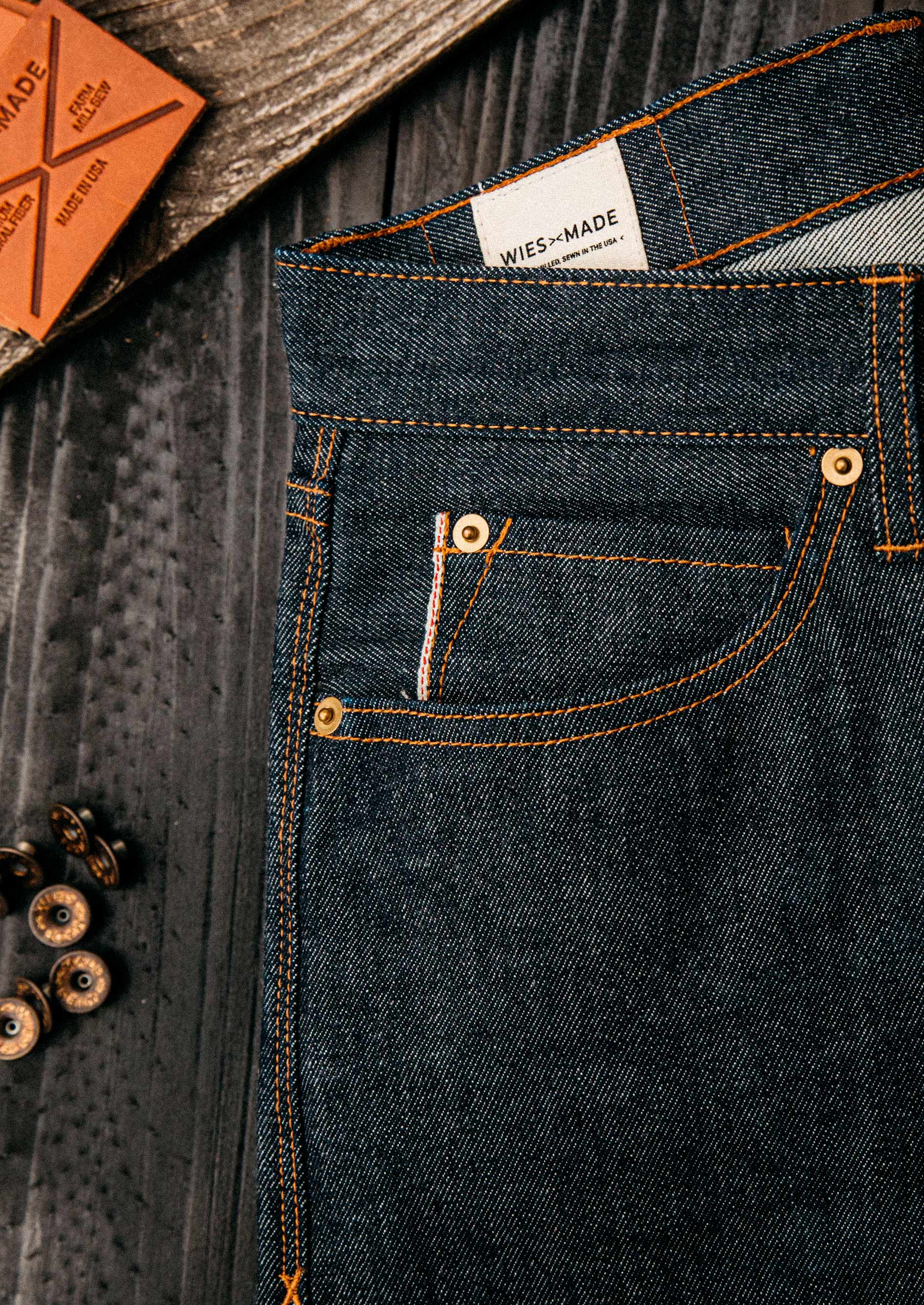 American selvedge denim jeans close-up showcasing premium raw denim texture, copper rivets, and contrast stitching, emphasizing authentic craftsmanship and durable construction made in the USA